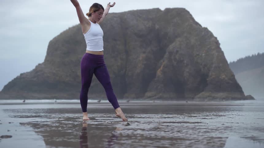 Woman performs yoga on the muddy beach on a cloudy day