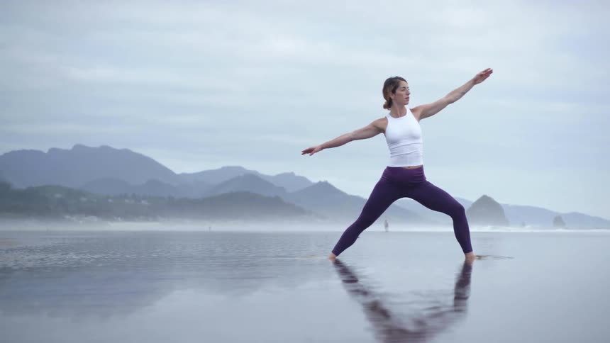 A woman does yoga on the beach