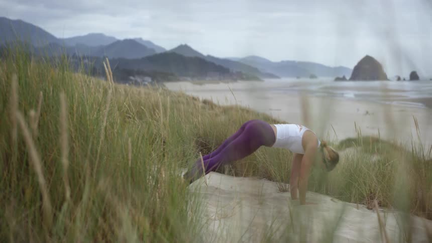 A woman is stretching outdoors by the beach