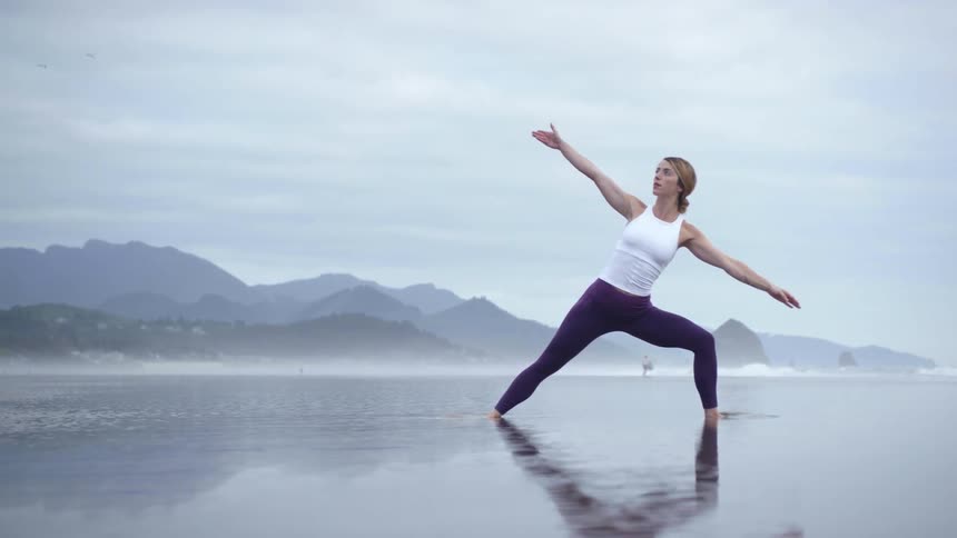 A woman doing yoga on a misty beach