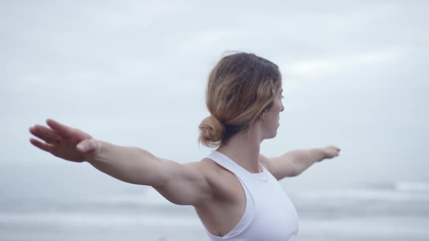 A young woman does yoga on the beach