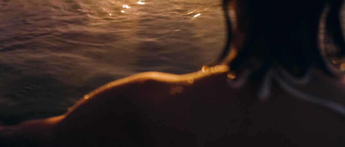 A woman sitting in shallow, steamy water waving her arms through the water