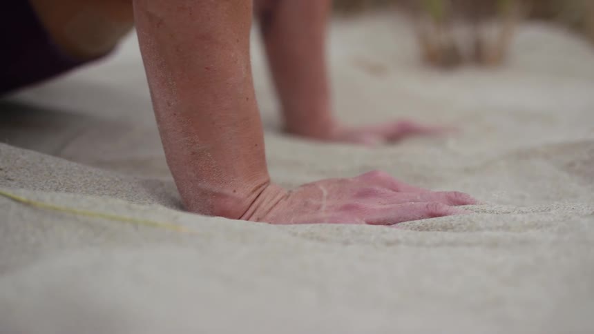 A man has his palms face down on the sand