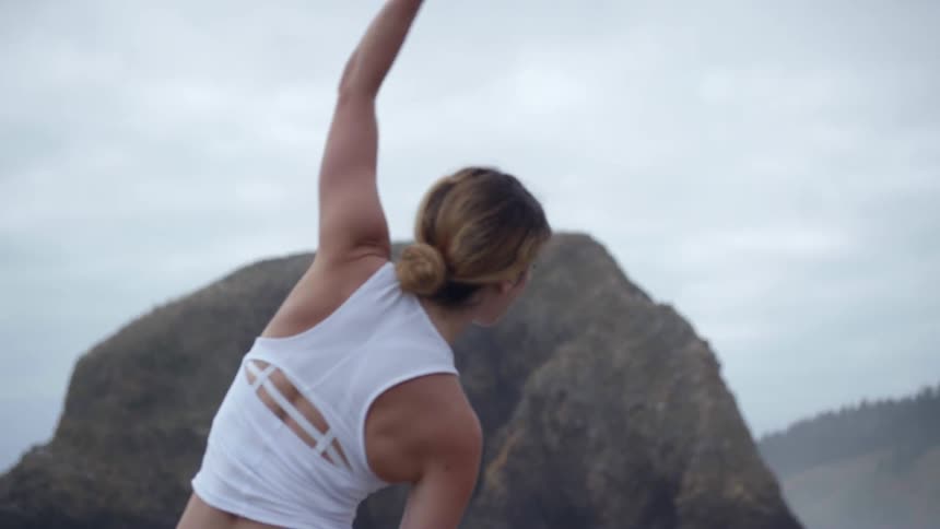 Woman performs yoga on the beach on a cloudy day