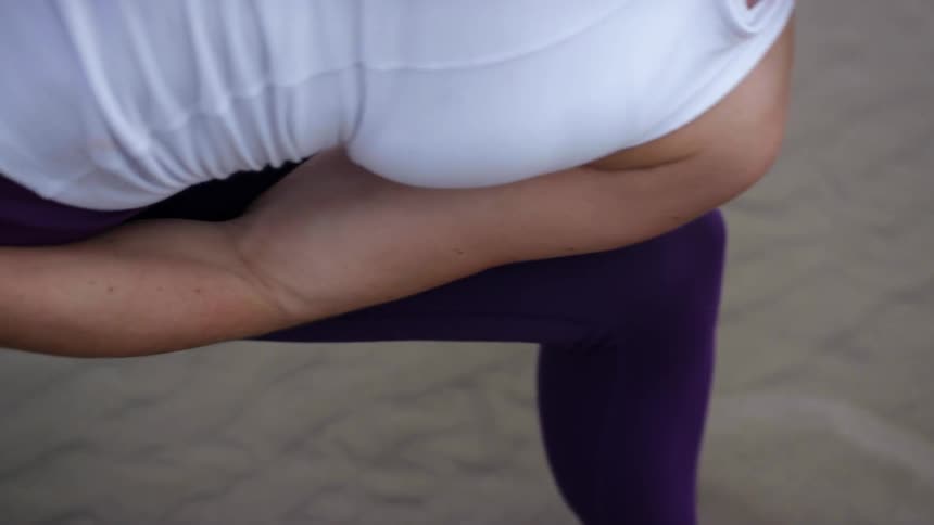 A woman stretches in a yoga pose on the beach
