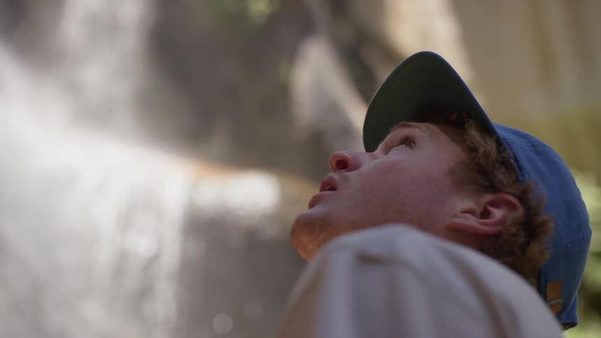 A person looks up at a waterfall