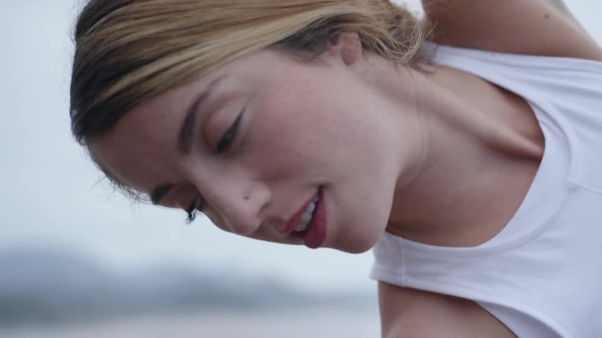 Blonde woman smiling practices yoga on the beach on a cloudy day