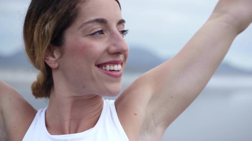 A woman smiling while doing stretches outdoors