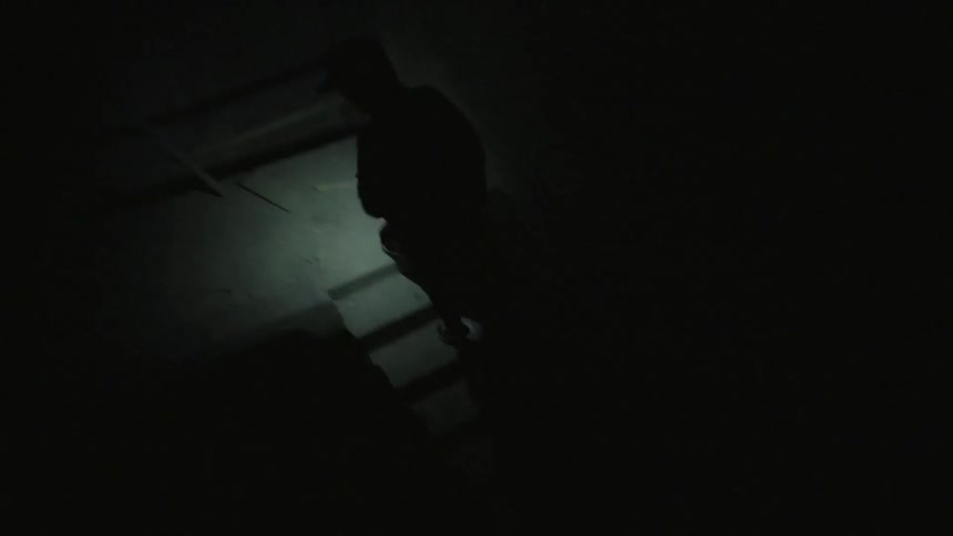 Man going up stairs in complete darkness with only a flashlight
