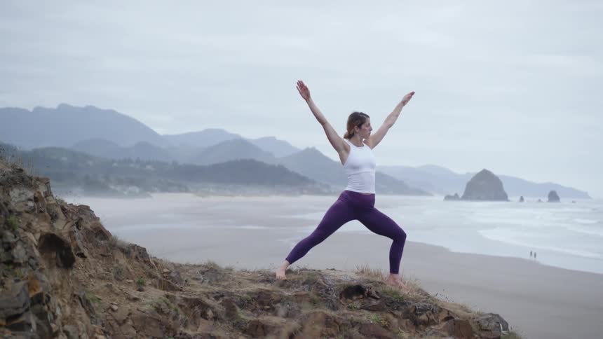 A woman is doing yoga on the beach