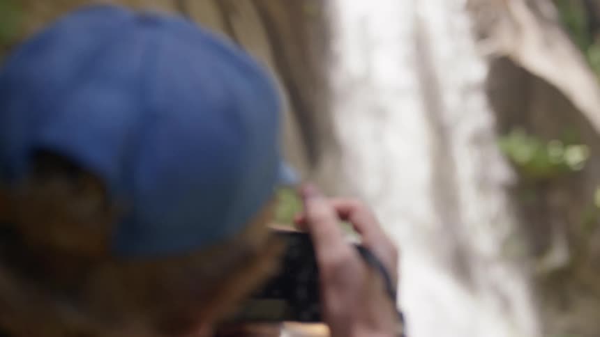 A man with a camera takes photos of a waterfall
