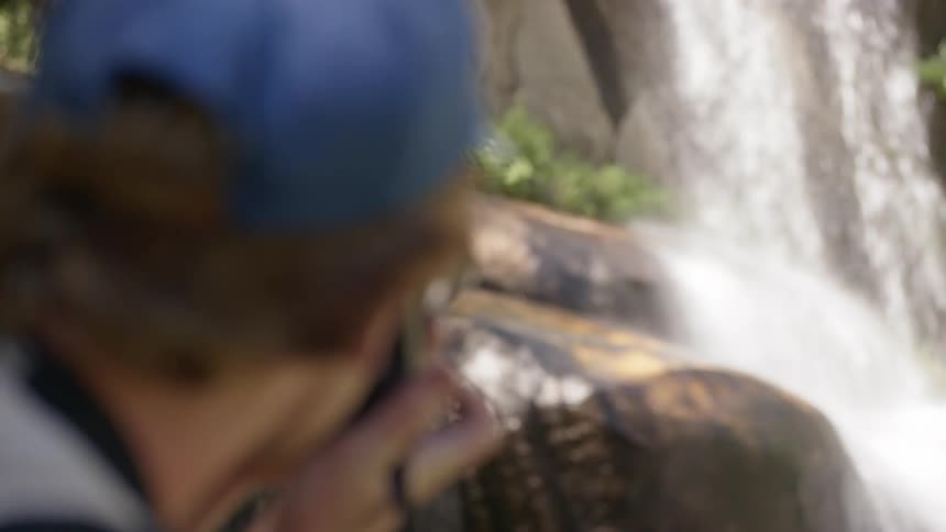 Male photographer takes a picture of the waterfall in the forest