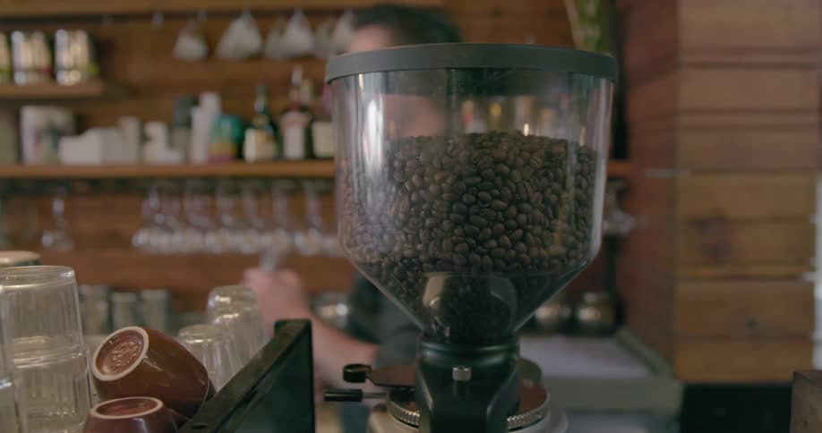 A man walks past a coffee grinder inside of a cafe