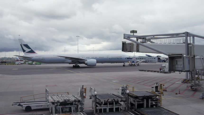 An airliner slowly backs up at an airport on a cloudy day