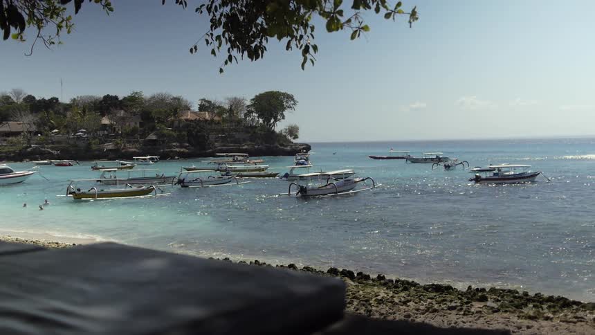 Boats docked on a quiet beach near a village