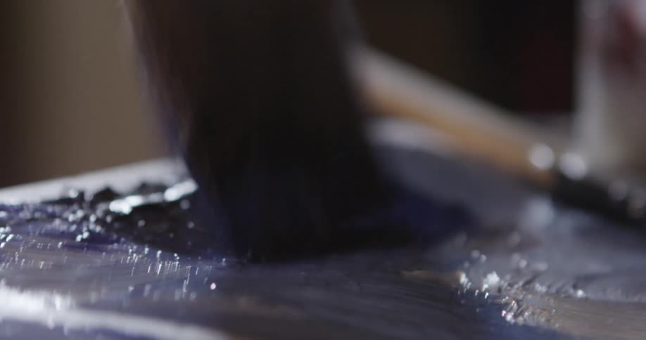 Paint brush stroking back and forth in a glob of blue paint
