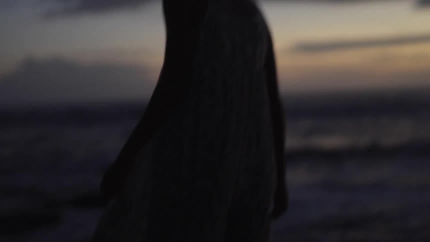 A woman walking on the beach with the sky in the background
