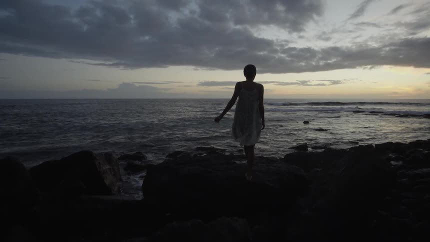 A woman walks to the ocean