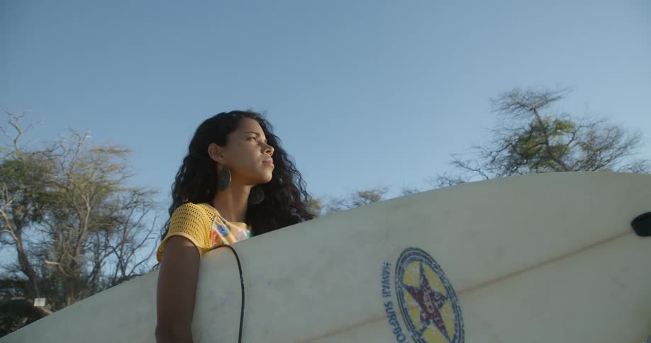 A woman standing outdoors holding a surf board