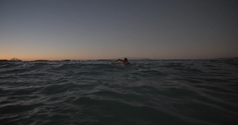 A man swims with his surfboard