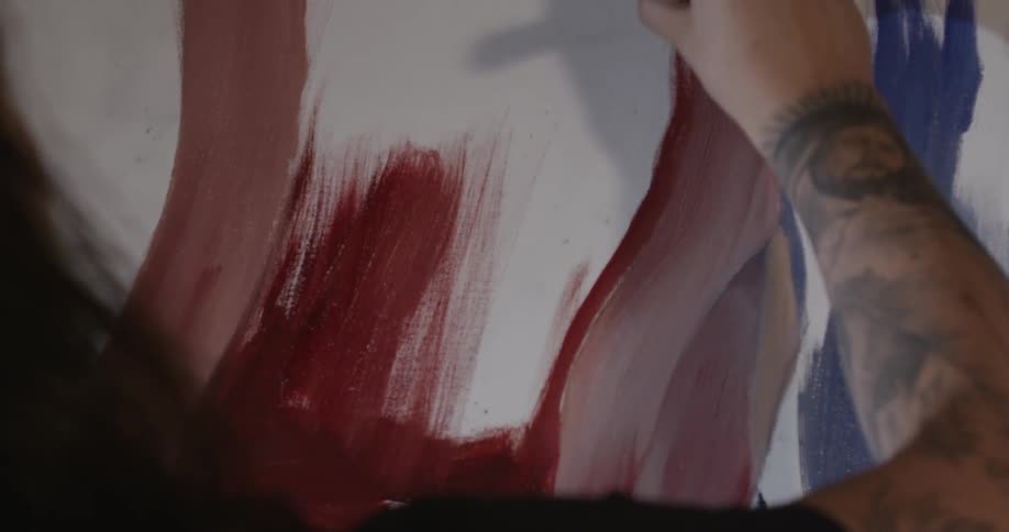 A person paints with red paint and a brush