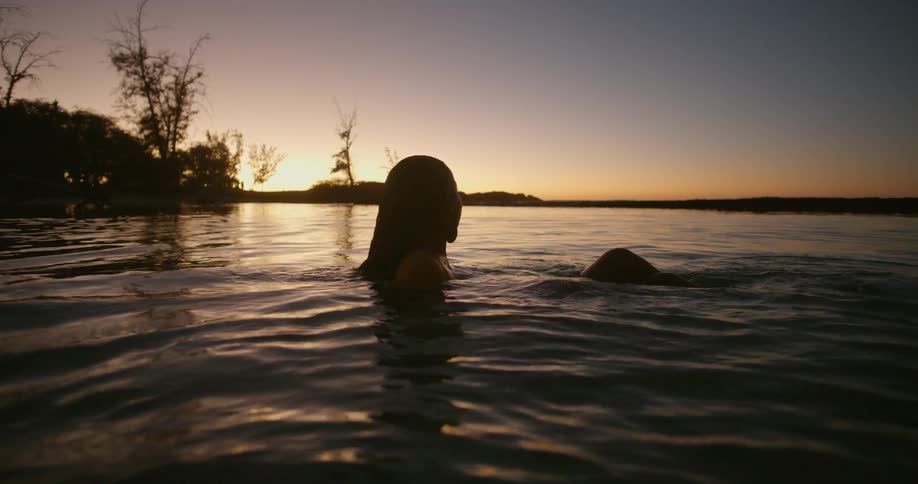 A woman bathes in the lake at sunset