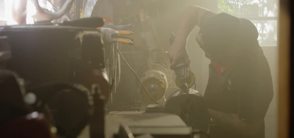 Man grinding a muffler in his workshop
