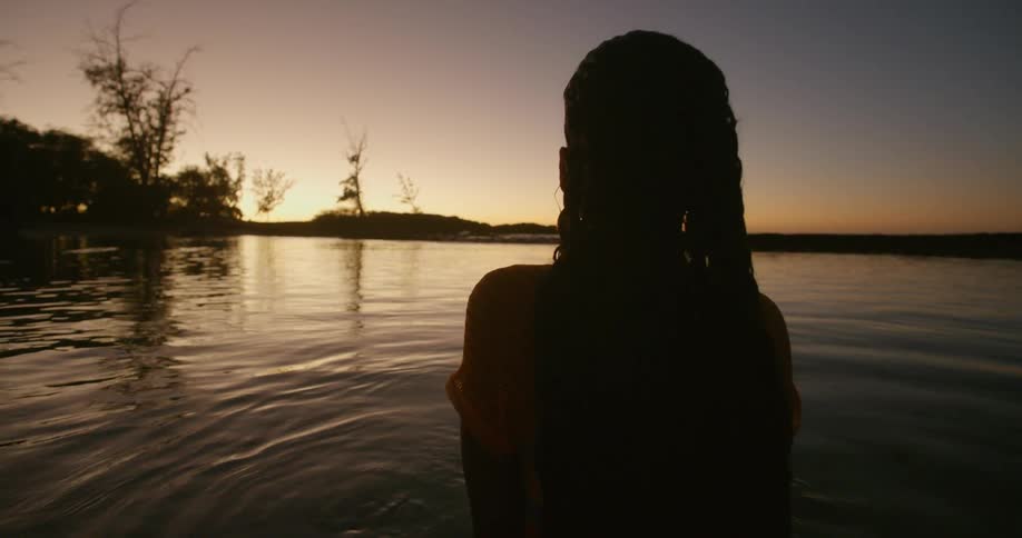 A woman standing in a lake with the sky in the background
