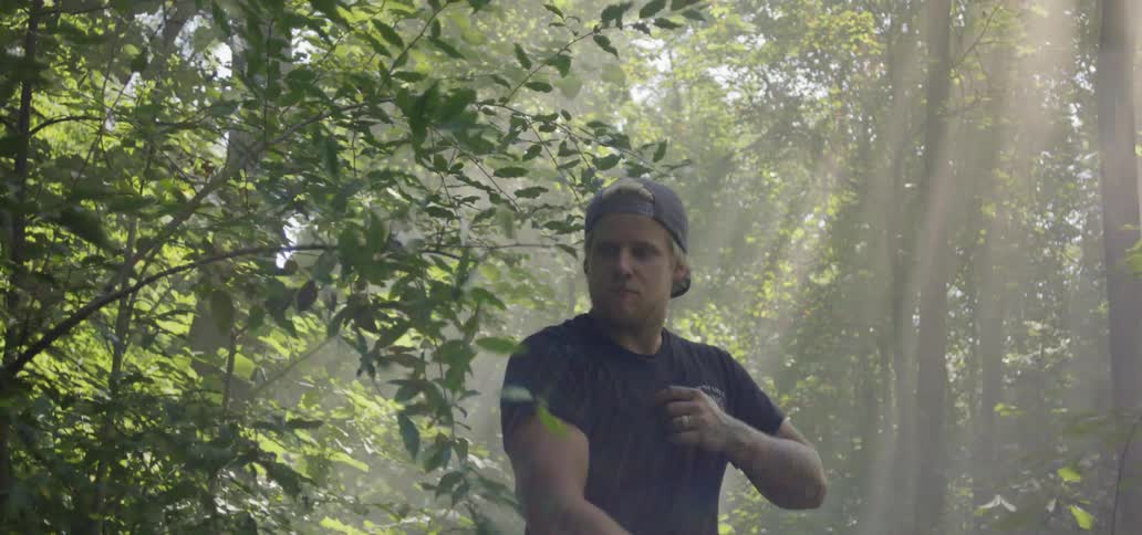 Man swings a big knife at the tree branch in the forest