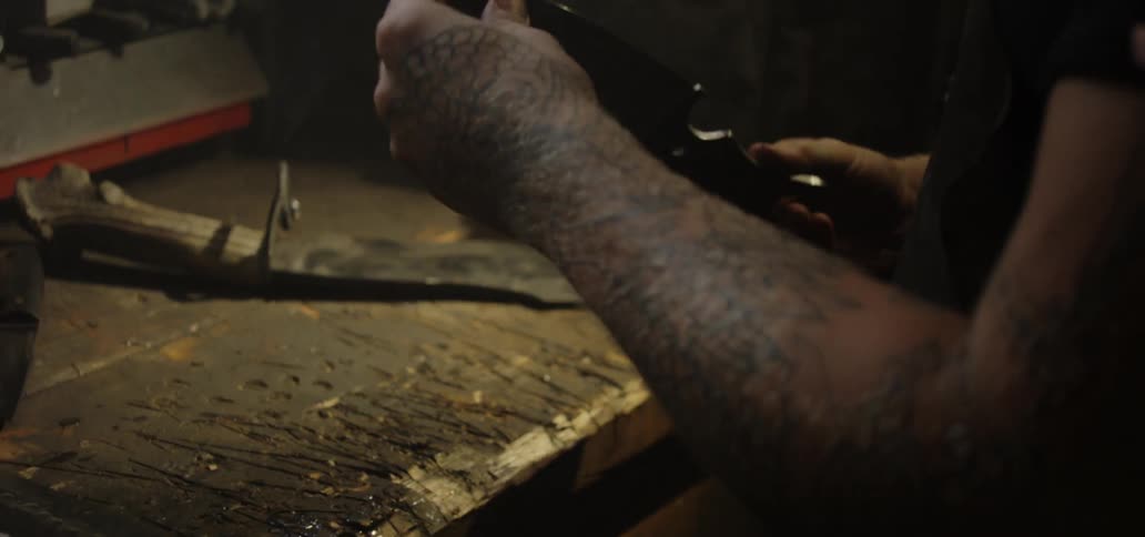 A man putting on glasses to examine a blade in a workshop