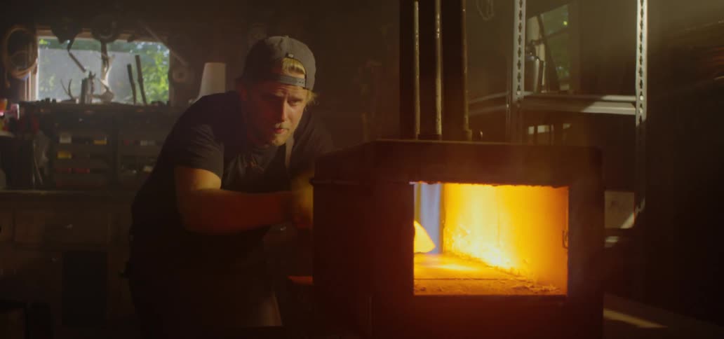Man works with metal in furnace oven in workshop
