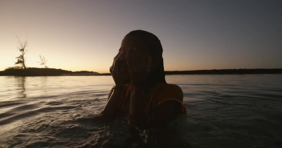 Woman stands in water looking toward shore
