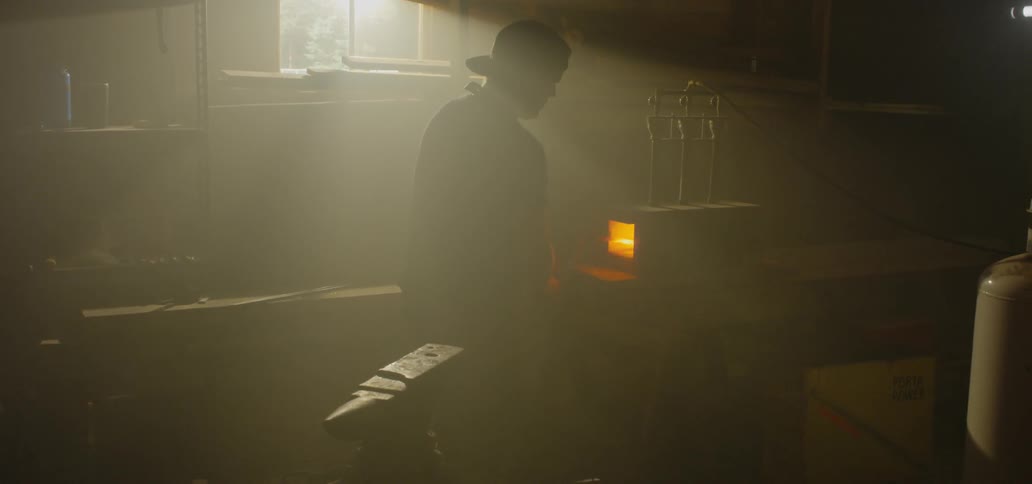 Blacksmith takes hot metal blade to forge