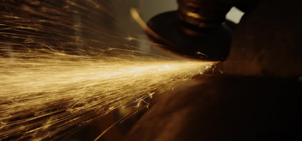 Sparks fly as a man uses a saw on a piece of metal