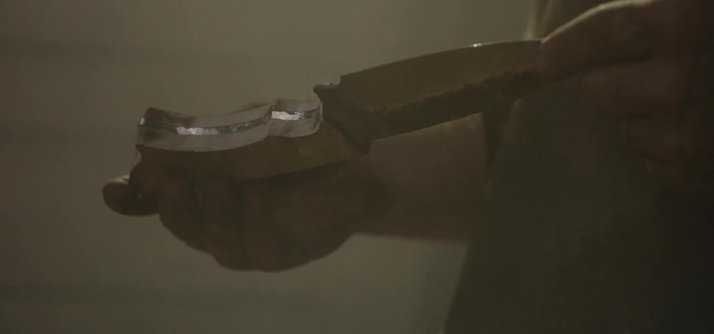 Man with tattoo holds and checks out the knife in the workplace