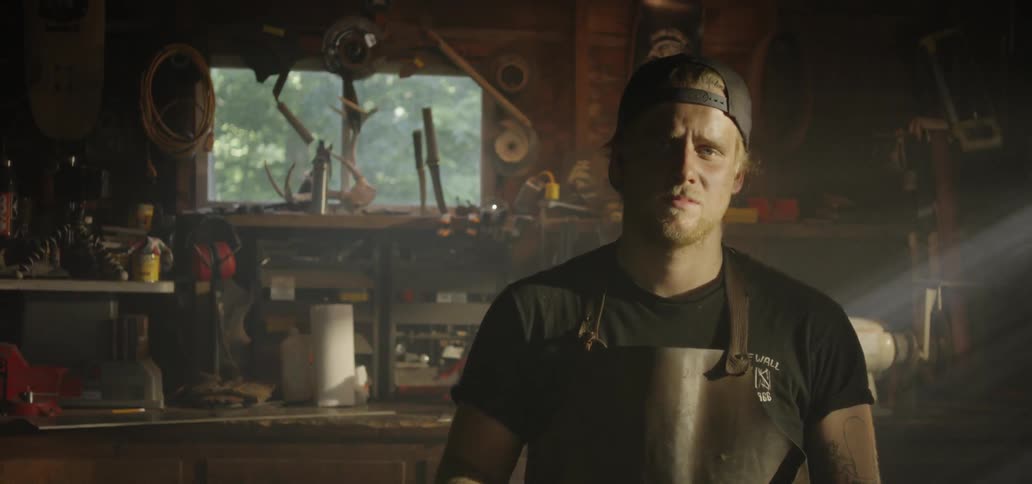 A blacksmith picks up his hammer and poses for the camera