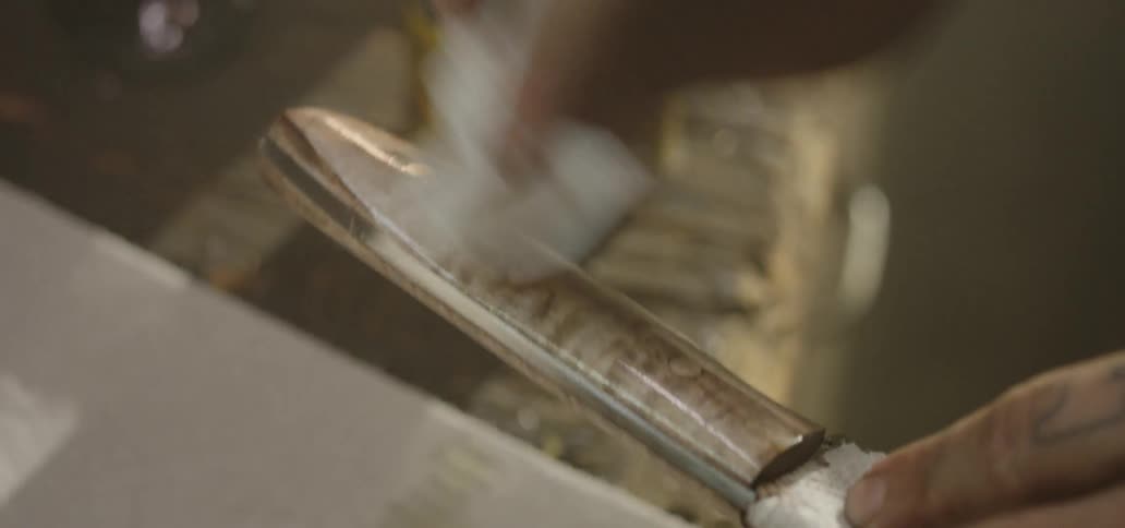 A person wiping the wooden handle of a knife with a cloth
