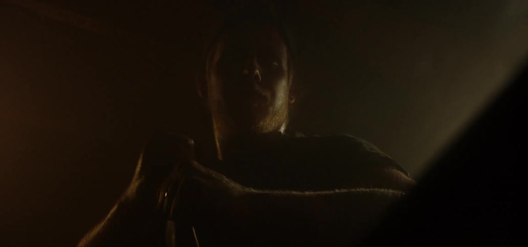 A man is holding a red hot piece of steel and quenches it
