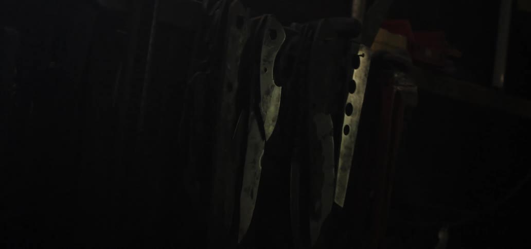 Blades without handles hanging from nails in a dark workshop