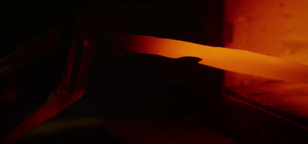 A person pulls a hot piece of metal out of a forge