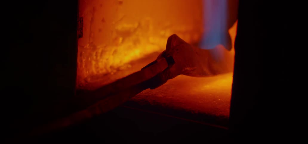 A blade being held in a forge with a pair of tongs