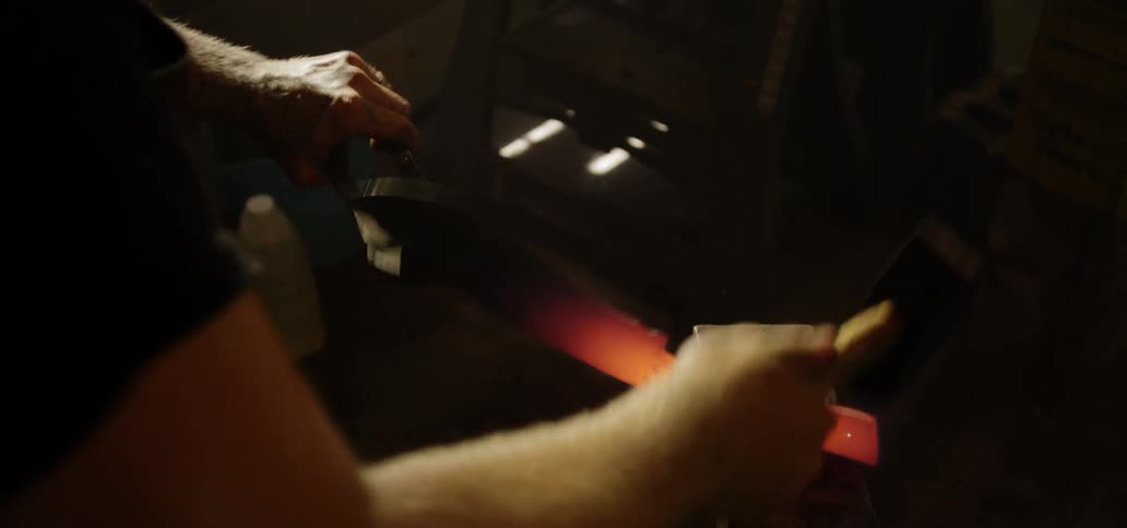 A man hammers red hot metal