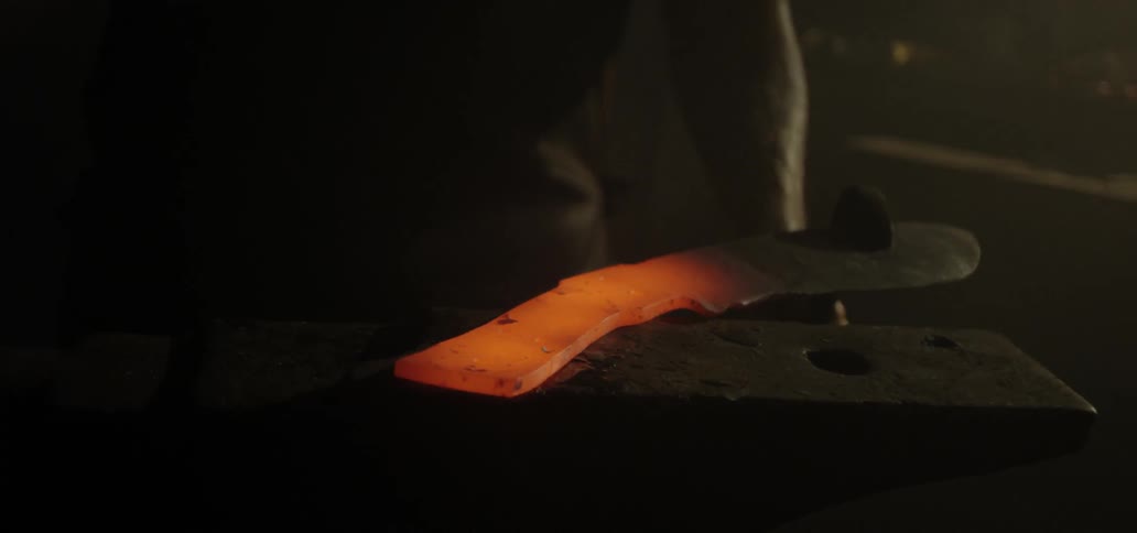 A blacksmith hammers a piece of hot metal