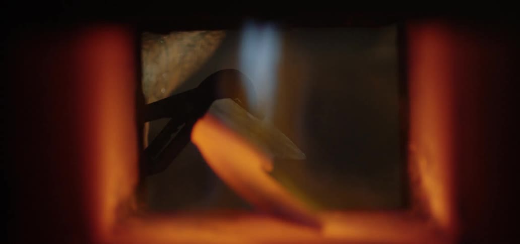 Flames heat up a piece of metal and a man pulls it out