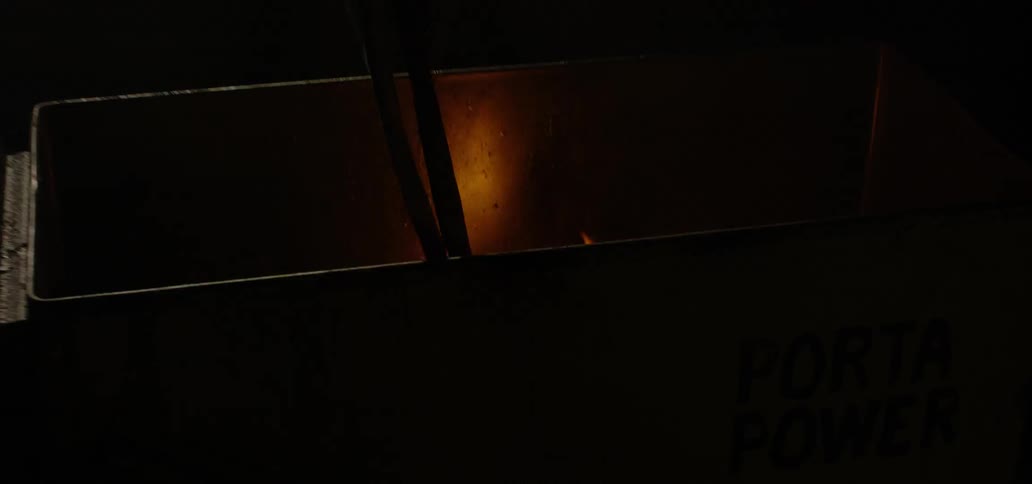 A blacksmith removes a hot piece of metal from a fire and puts it into water