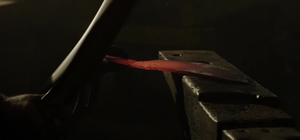 Blacksmith shapes metal with hammer