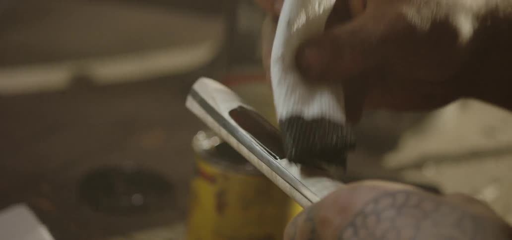A person dips a cloth into wood stain and paints it on an object