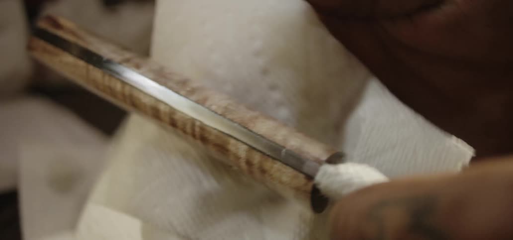 A man wipes the handle of a knife with a paper towel