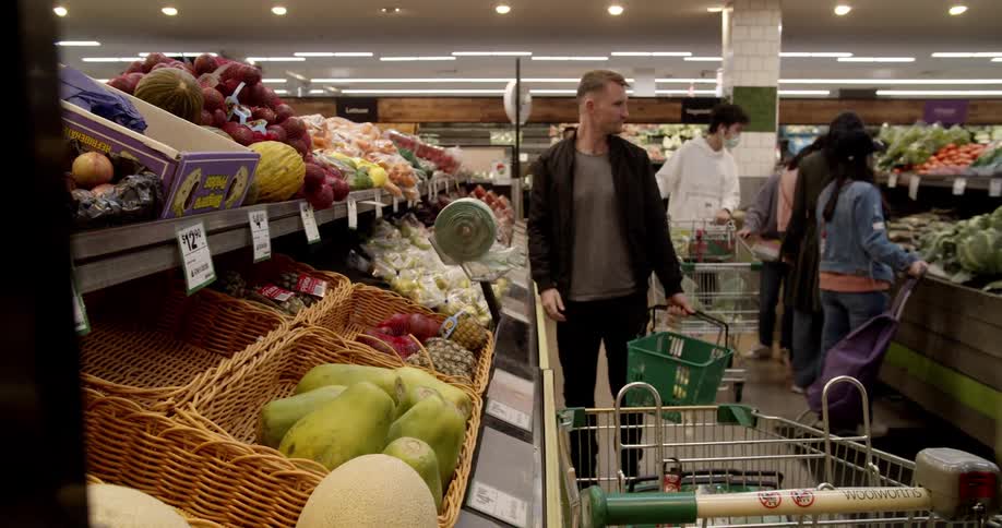 Woman wearing face mask selects cantaloupe