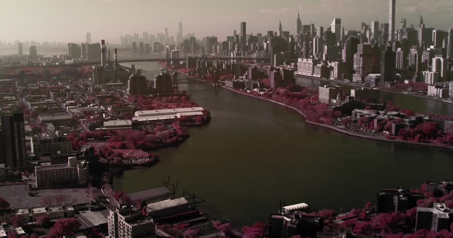 In the middle of a large metropolitan city a river runs through the middle and is spanned by a bridge